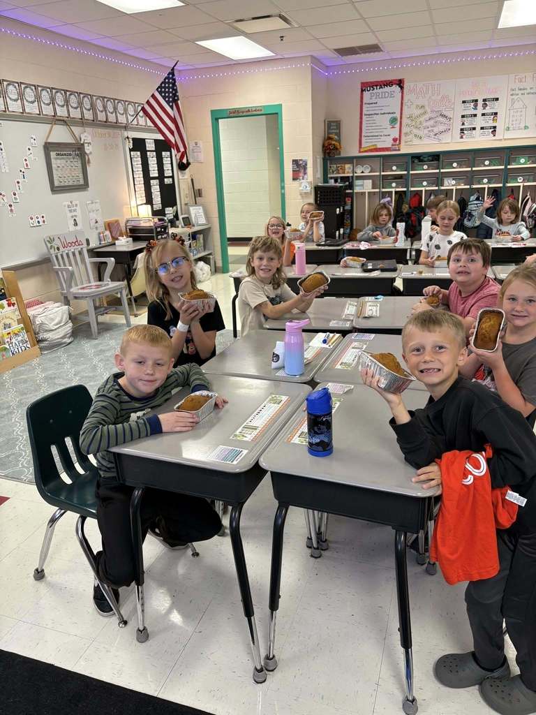Students smiling, holding their tins of pumpkin bread
