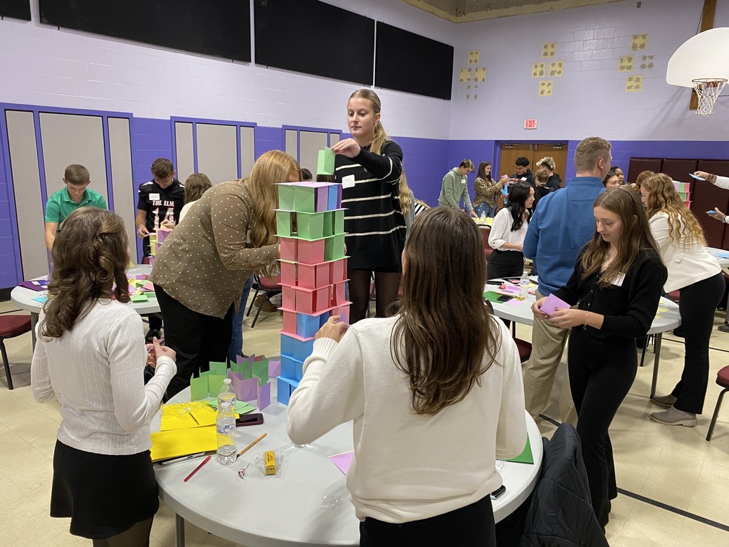 Students working together at Leadership Conference building paper tower