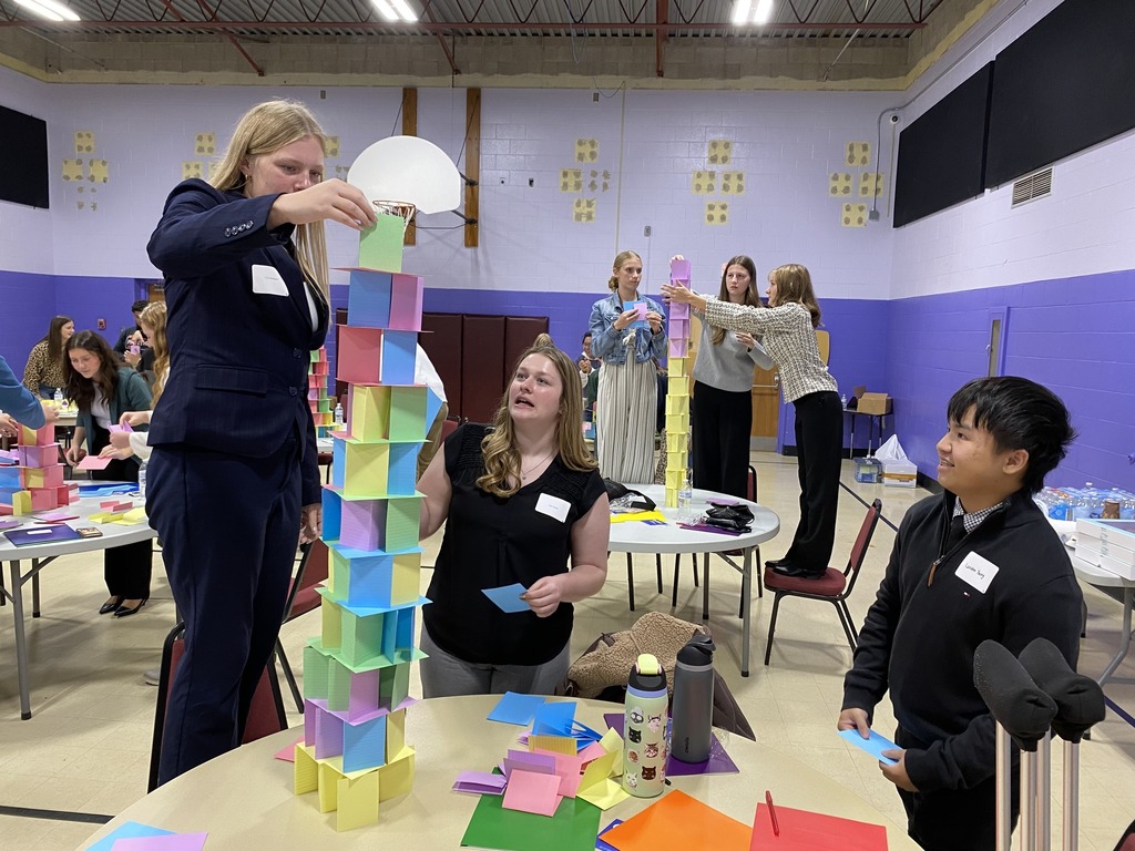 Students working together at Leadership Conference building paper tower