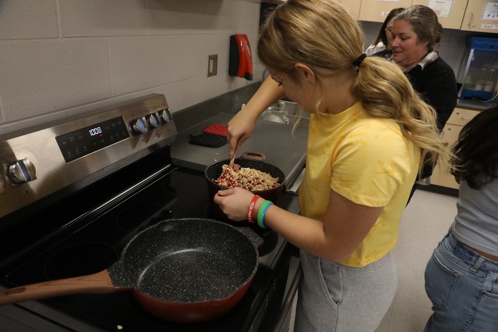 Student at stove making rice krispie treats in pot