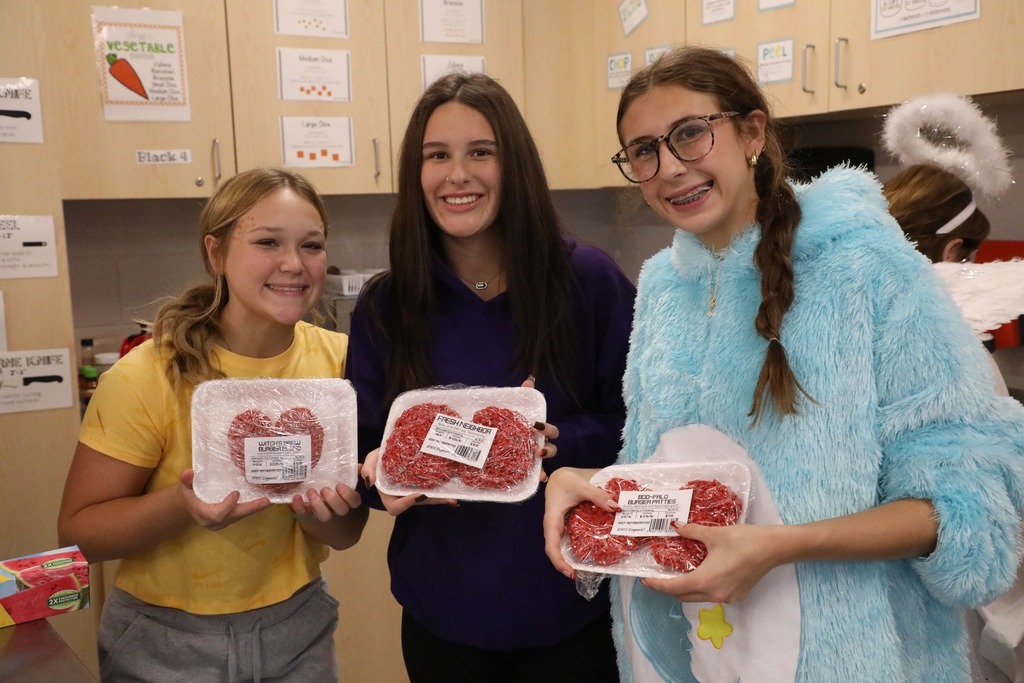 Students holding up rice krispie treat wrapped on a tray with plastic wrap
