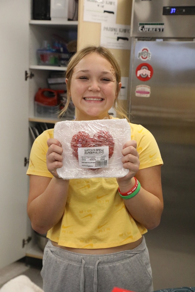 Student holding up rice krispie treat wrapped on a tray with plastic wrap