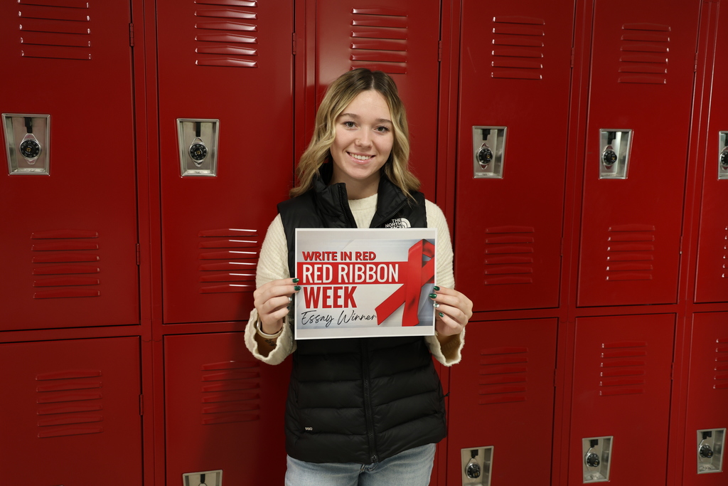 Kylie Fleming holding a paper that reads "Write in Red Red Ribbon Week Essay Winner"