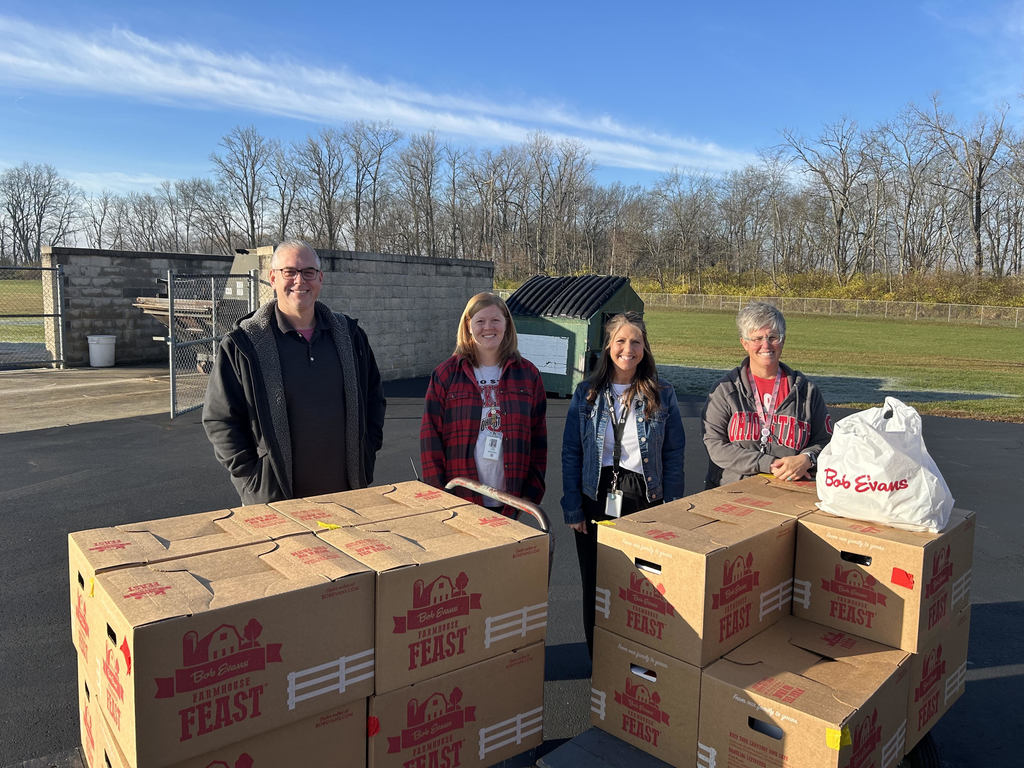 Counselors posing outside with boxes of food labeled Bob Evans Feast