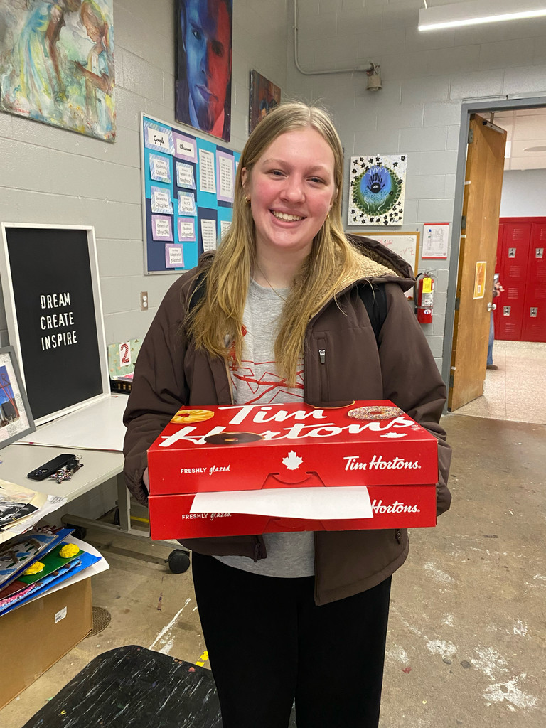 Student holding a box of donuts smiling