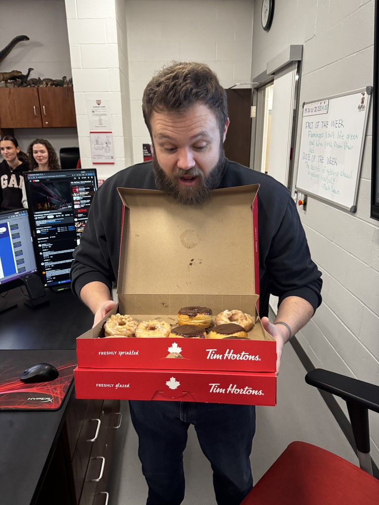 Teacher holding box of donuts with a surprised look on his face