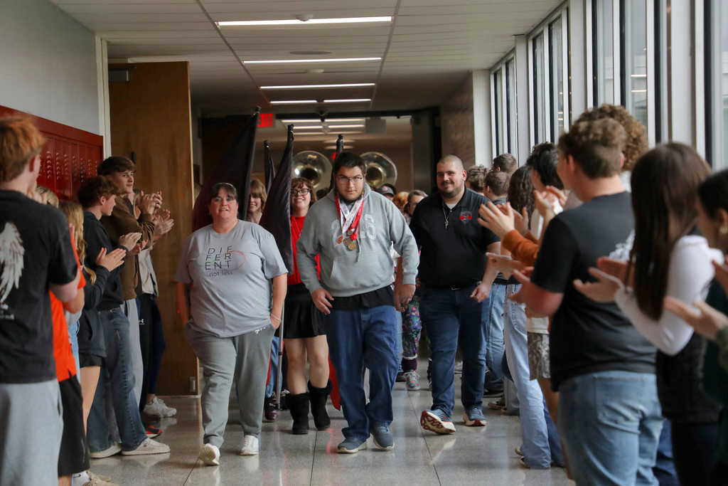 Ashton Carpenter walking through a hallway lined with students clapping and cheering