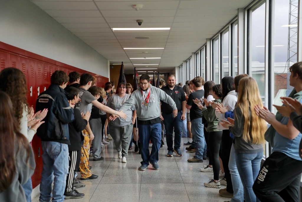 Ashton Carpenter walking through a hallway lined with students clapping and cheering