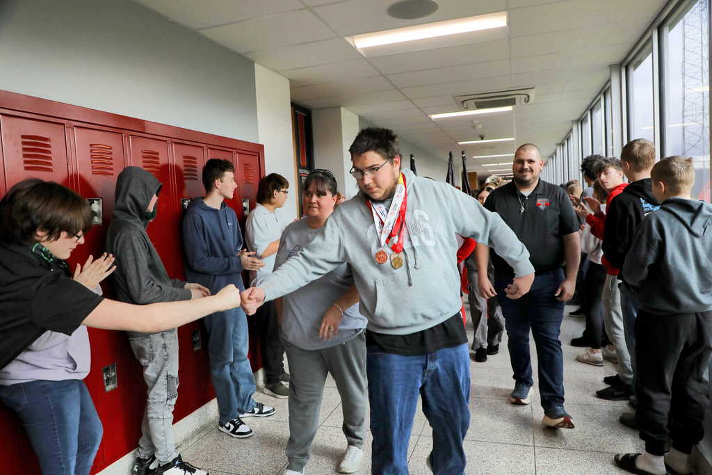 Ashton Carpenter walking through a hallway lined with students clapping and cheering