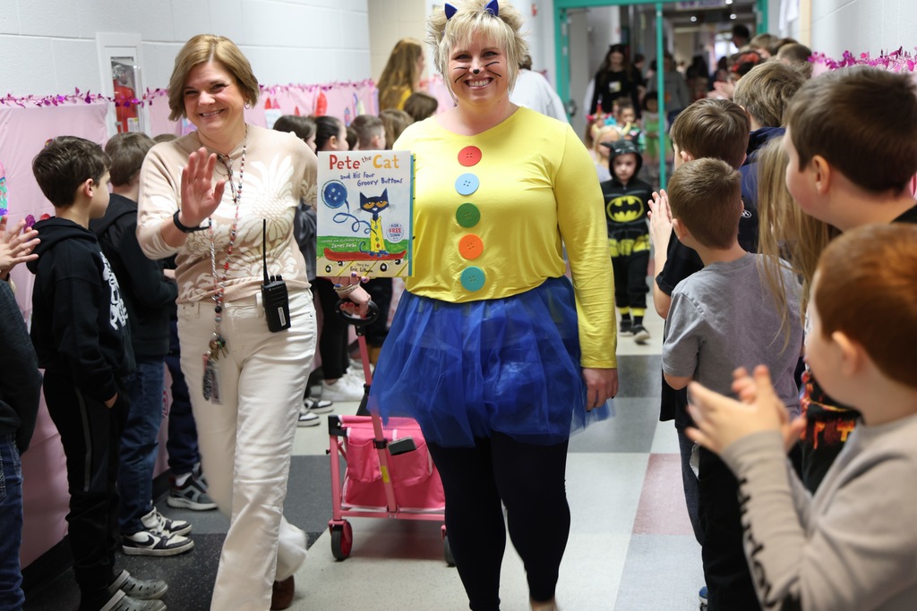 two female women posing in student-lined hallway