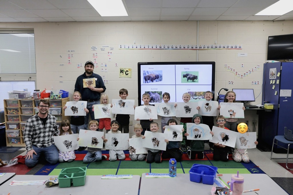 Students and Adults posing with drawings and book