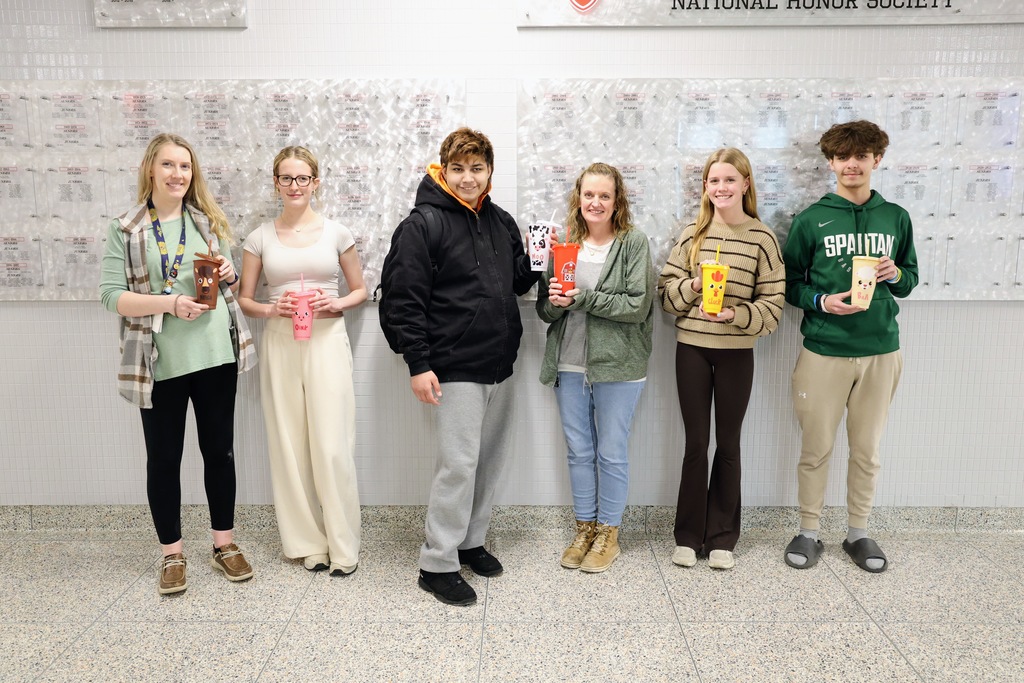 Students and staff members posing with farm animal style cups