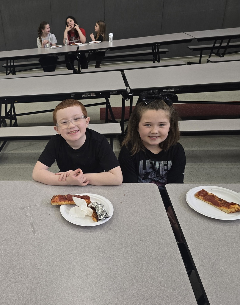 Students posing and smiling with plates of pizza