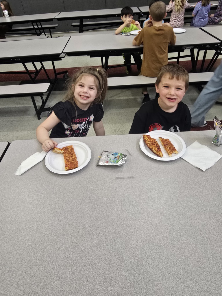 Students posing and smiling with plates of pizza
