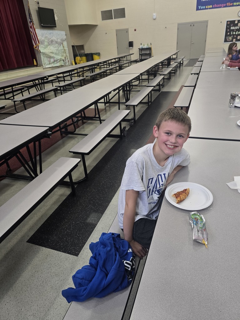 Students posing and smiling with plates of pizza