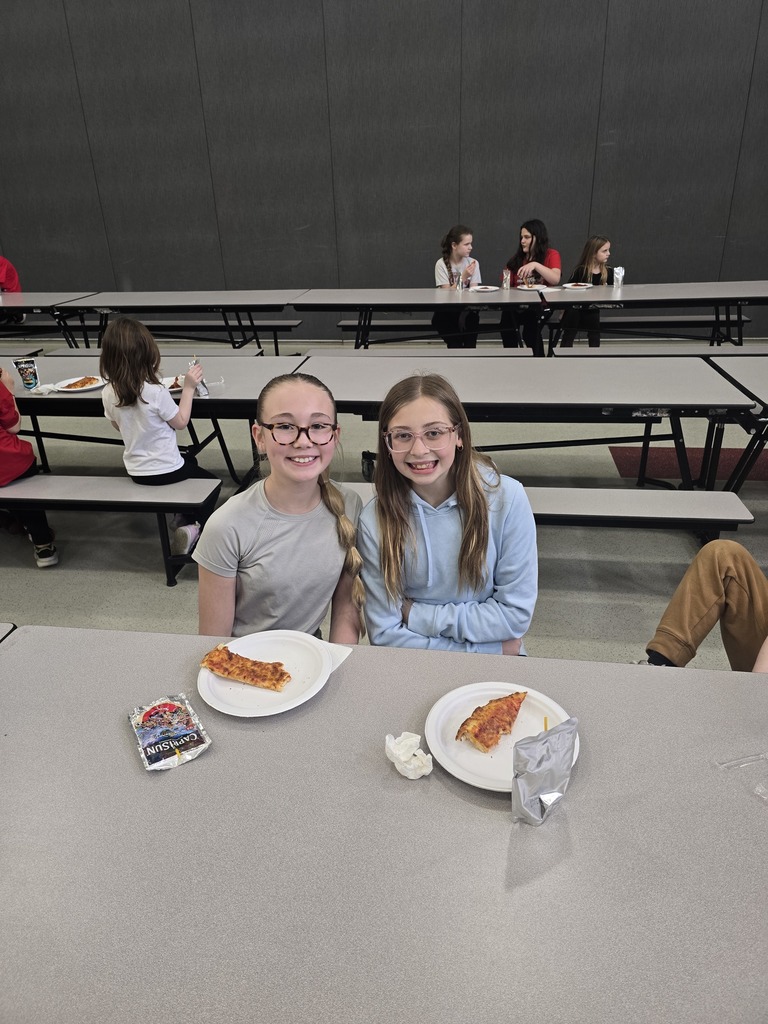 Students posing and smiling with plates of pizza