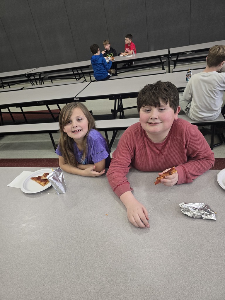 Students posing and smiling with plates of pizza