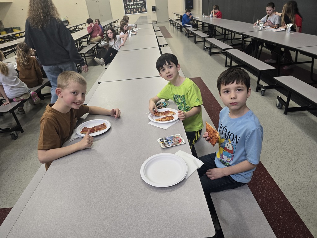 Students posing and smiling with plates of pizza
