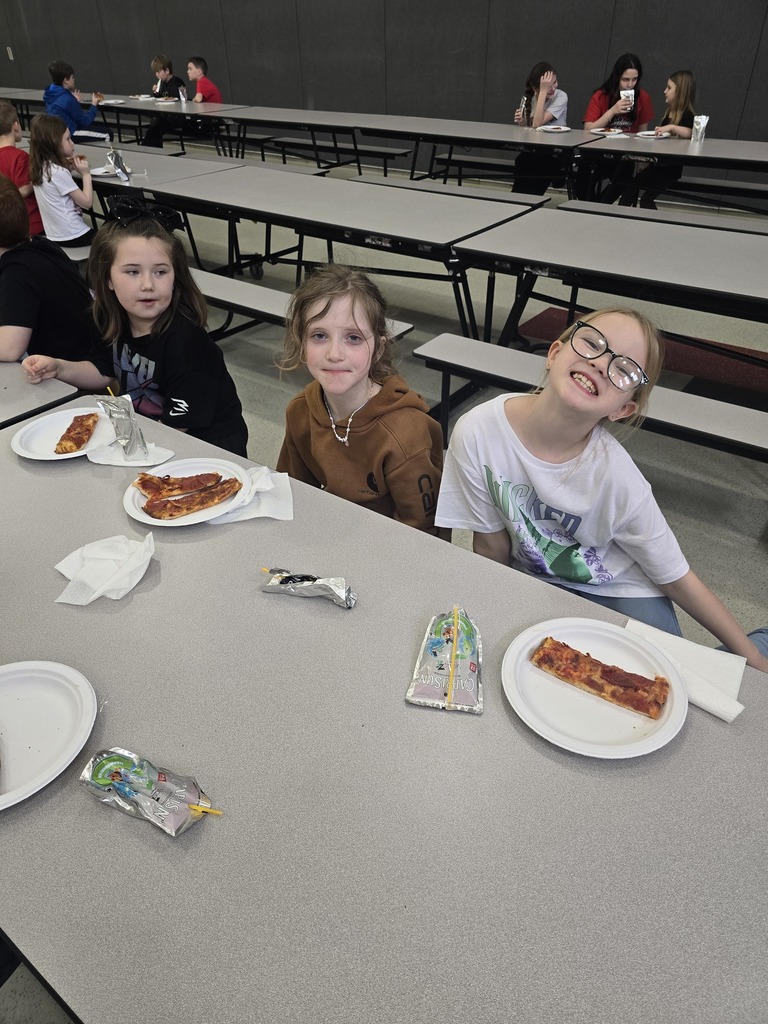 Students posing and smiling with plates of pizza