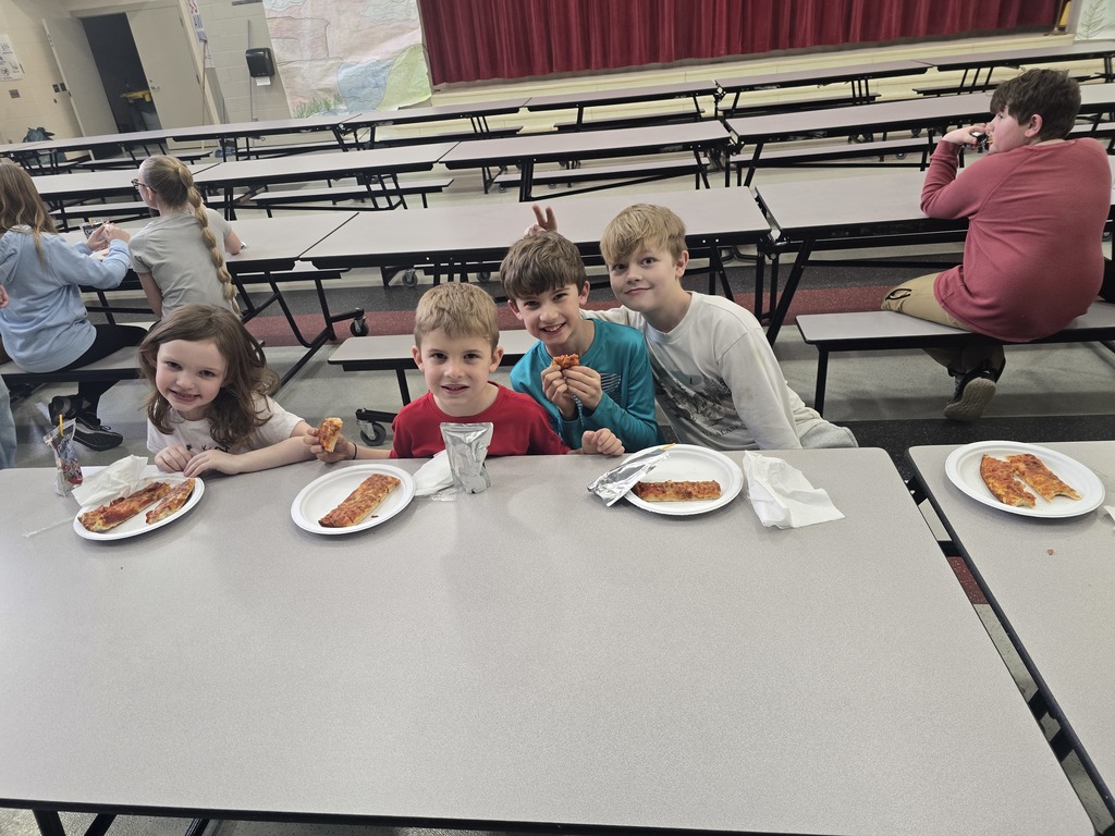 Students posing and smiling with plates of pizza