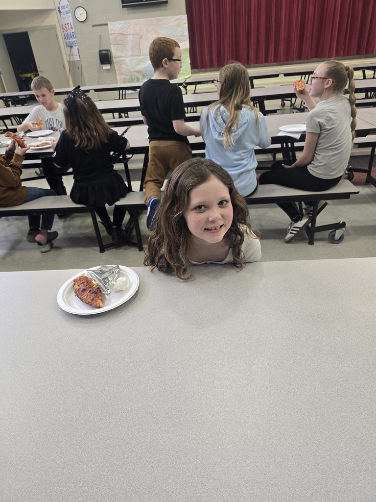 Students posing and smiling with plates of pizza