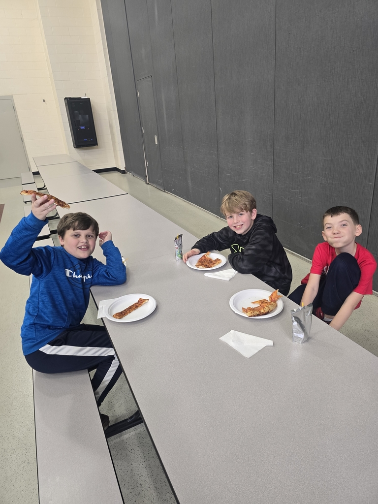 Students posing and smiling with plates of pizza