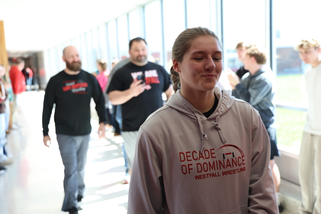 Female wrestler smiling with coaches walking behind her