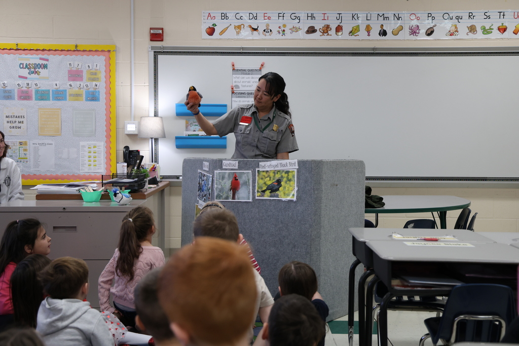 Park Ranger showing off birds to students sitting in front of a display of Ohio bird pictures