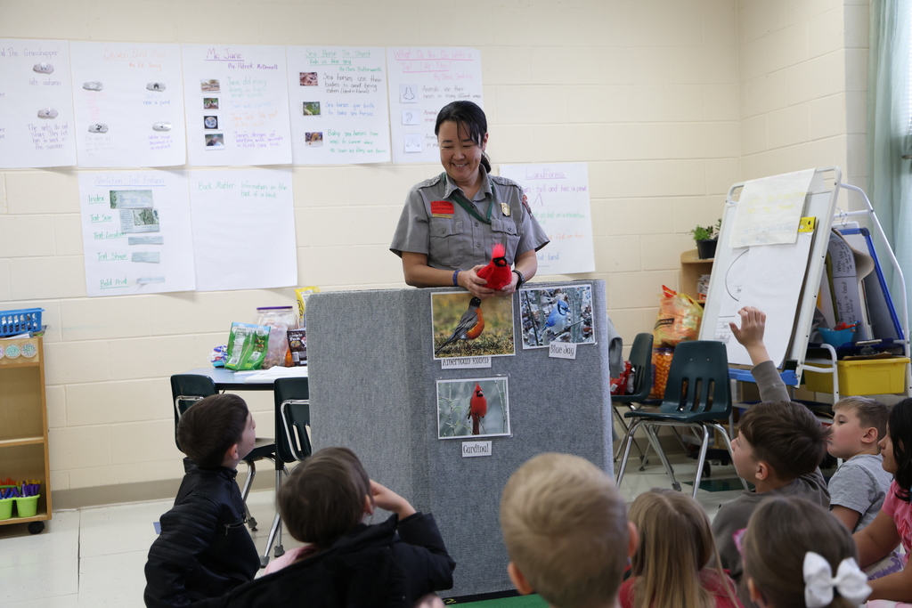 Park Ranger showing off birds to students sitting in front of a display of Ohio bird pictures
