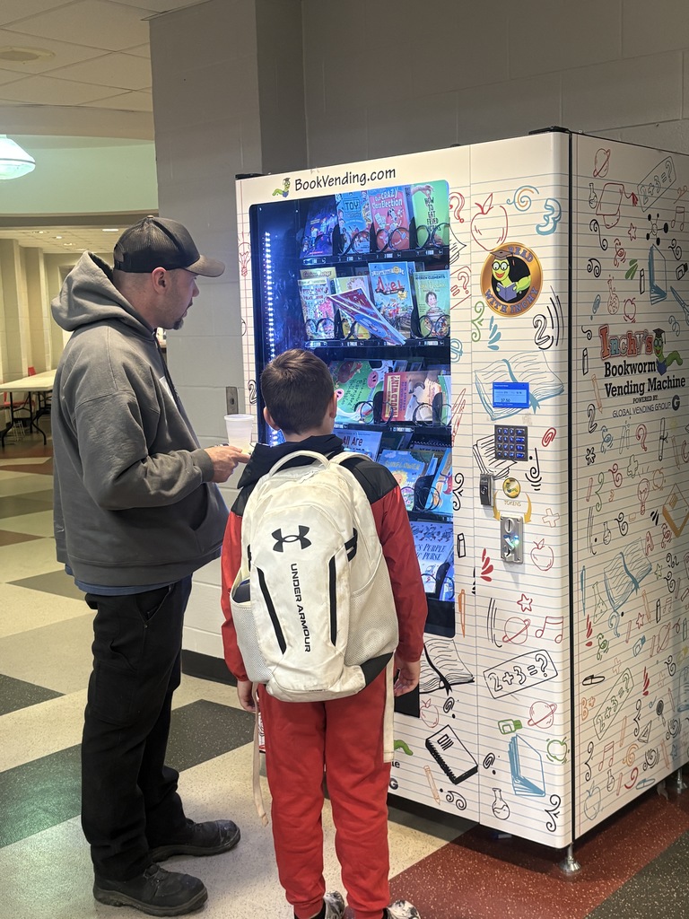 Student with white backpack stands in front of a white book vending machine with his father