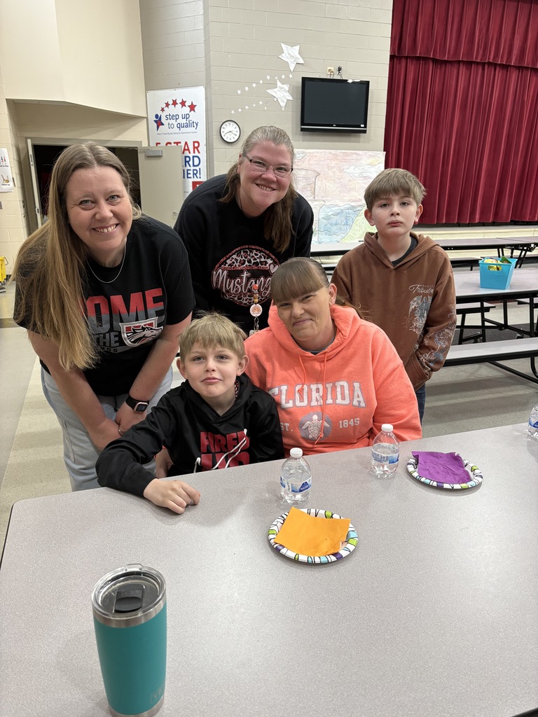 Students of the Month smiling with their parents and teacher