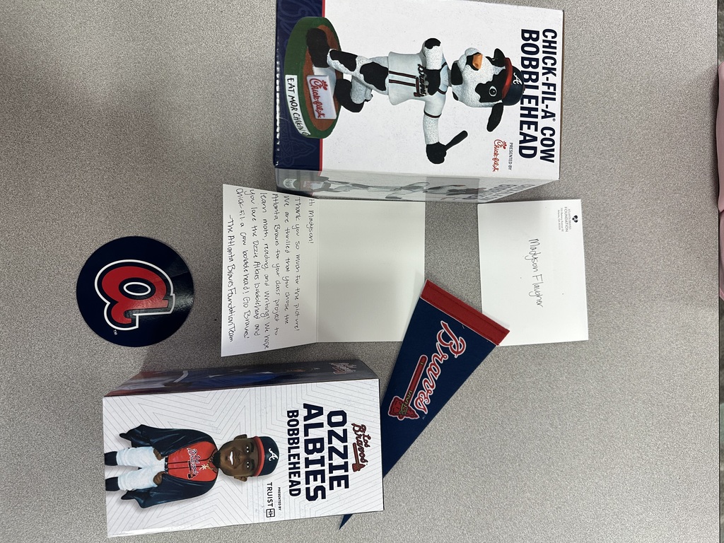two boxes containing bobbleheads, a letter, sticker and pennant on the table