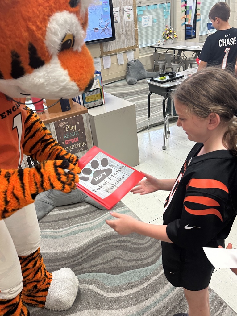Cincinnati Bengals mascot handing a female student a red booklet with a black paw print on the front 