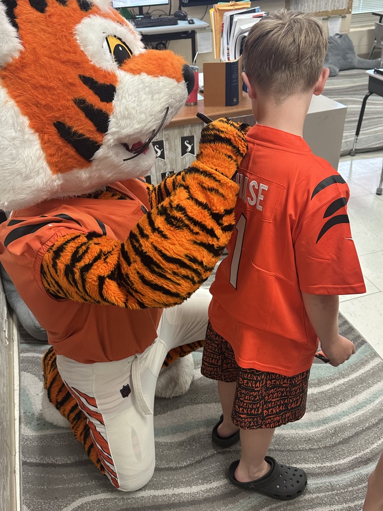 Cincinnati Bengals mascot signing a young boy's orange football jersey