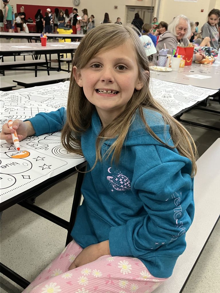 Student smiling at camera while coloring with markers