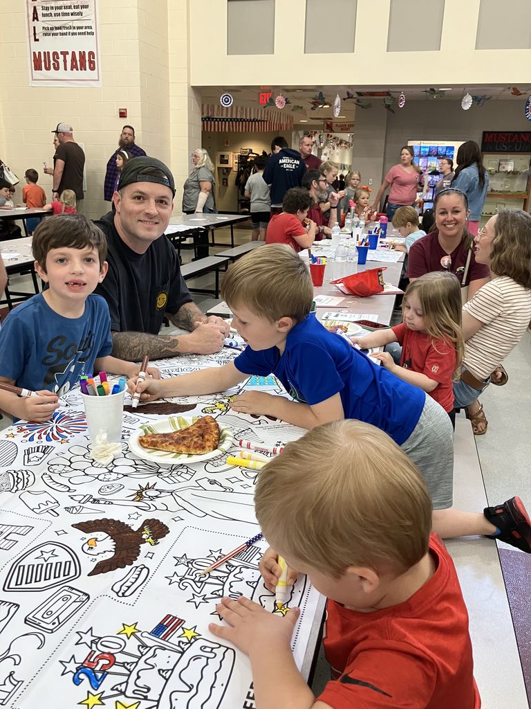 Students coloring on a large coloring page laid out across a table 