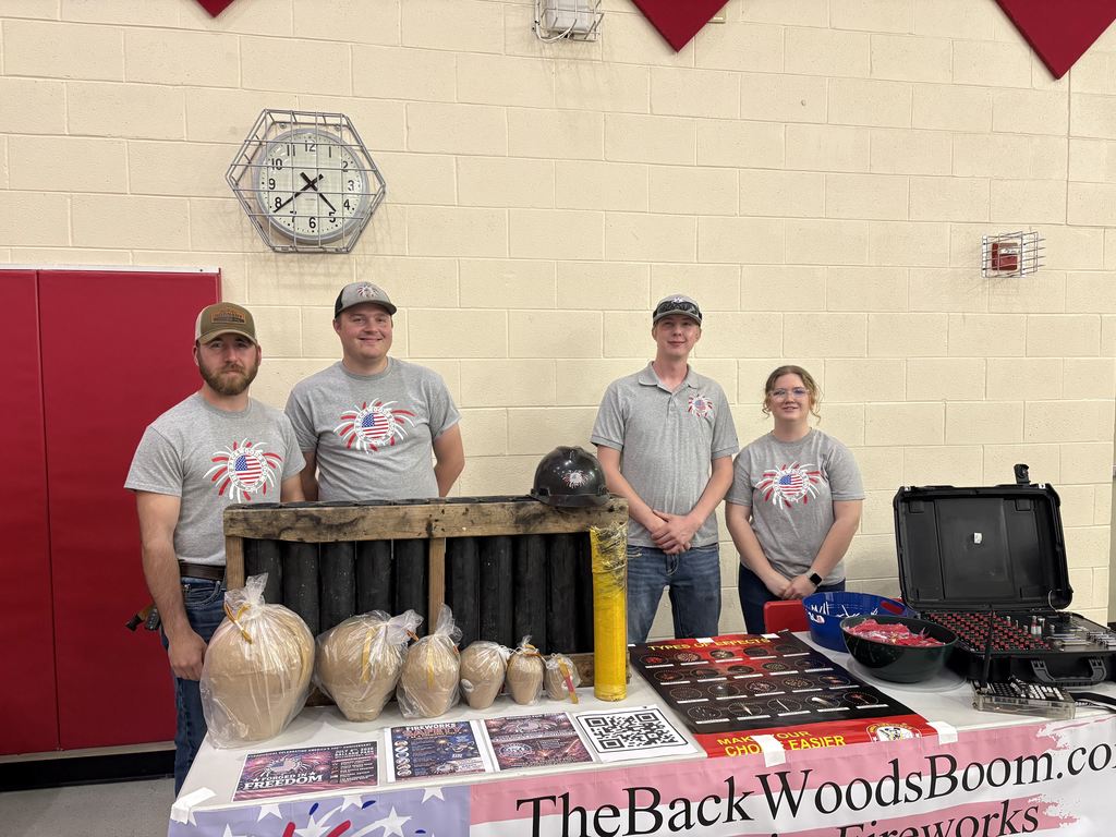 A groupd of patrons smiling at the camera while standing behind a table display for The Backwoods Boom