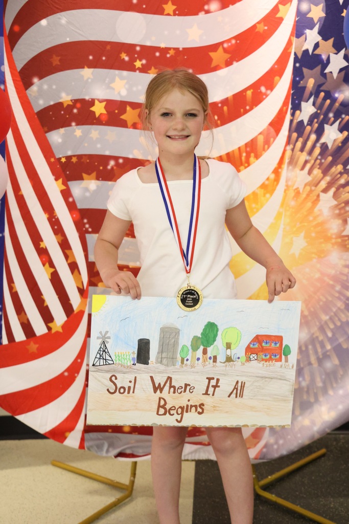 Kinsley Steward holding her artwork and wearing her medal
