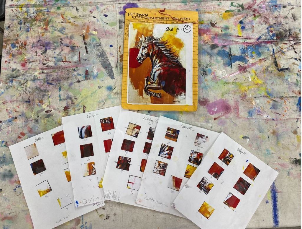 A top-down view displays several white worksheets scattered around a yellow envelope. Each worksheet is labeled with a student's name—Keller, Quinn, Ashley, Garrett, and Elijah—and contains small, square painted snippets taped into a grid. Resting on the envelope is the original reference artwork of the horse, which serves as the guide for the collaborative project.
