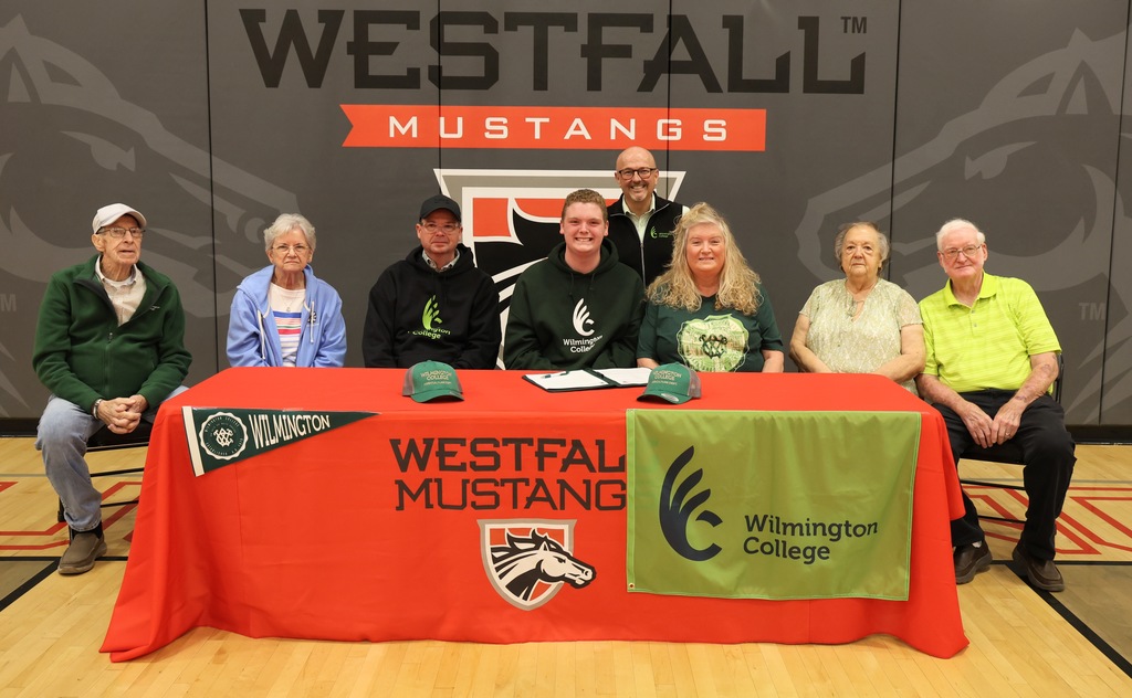 Dalton Bush and family sitting behind signing table decorated with Westfall tablecloth and Wilmington memorabilia