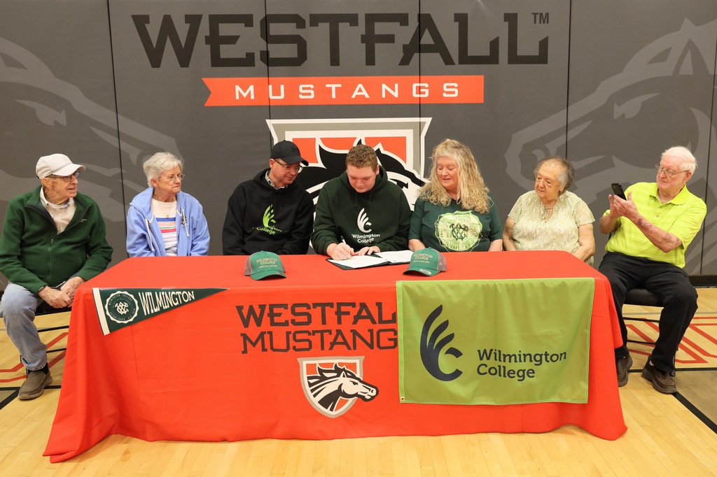 Dalton Bush and family sitting behind signing table decorated with Westfall tablecloth and Wilmington memorabilia