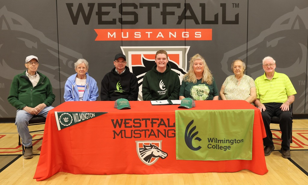 Dalton Bush and family sitting behind signing table decorated with Westfall tablecloth and Wilmington memorabilia