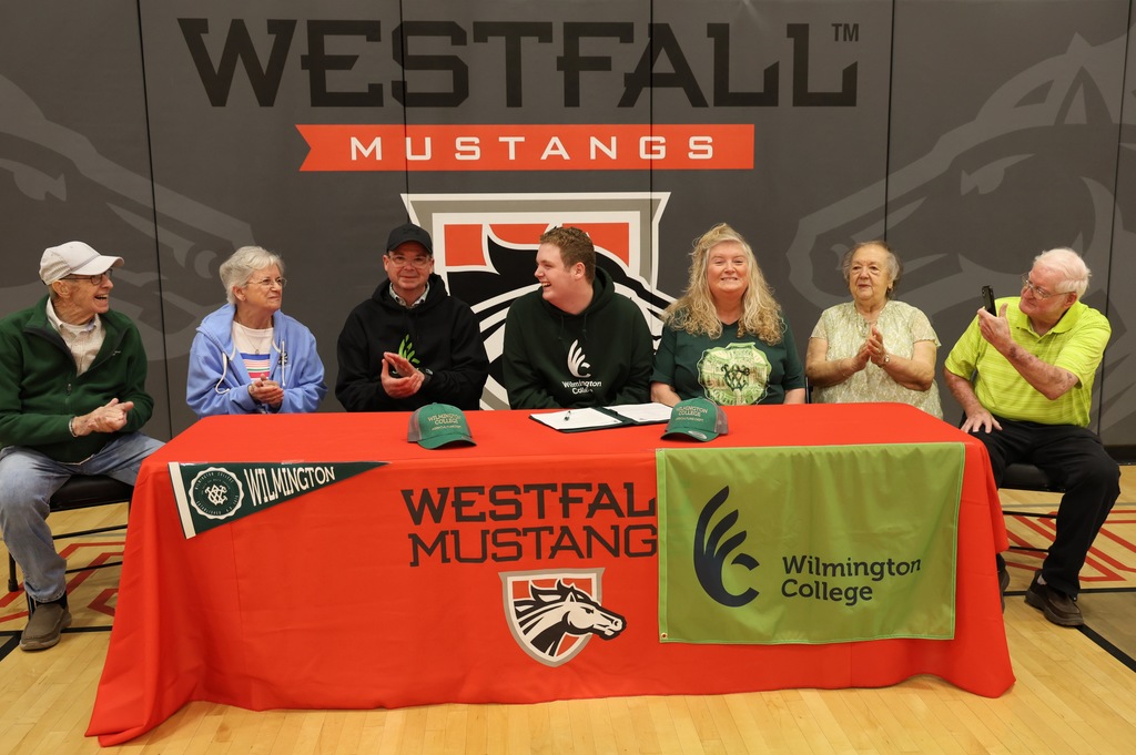 Dalton Bush and family sitting behind signing table decorated with Westfall tablecloth and Wilmington memorabilia