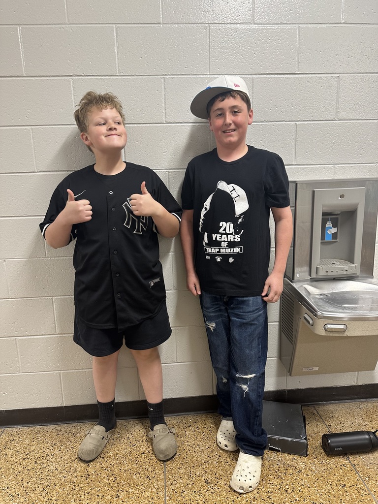 Two students standing next to each other, with one boy making double thumbs up