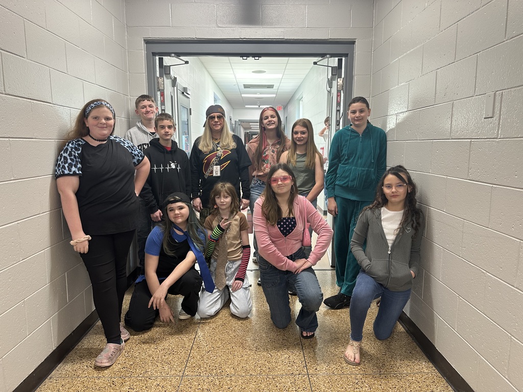 A group of students stand with a teacher in the hallway