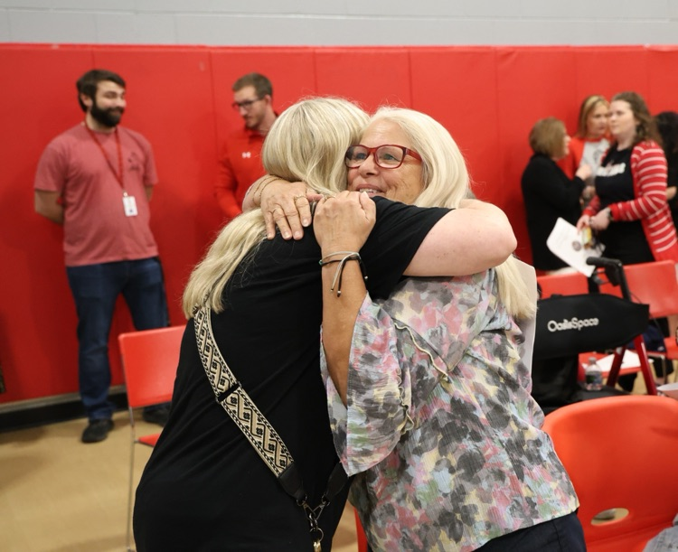 former staff member hugging another person