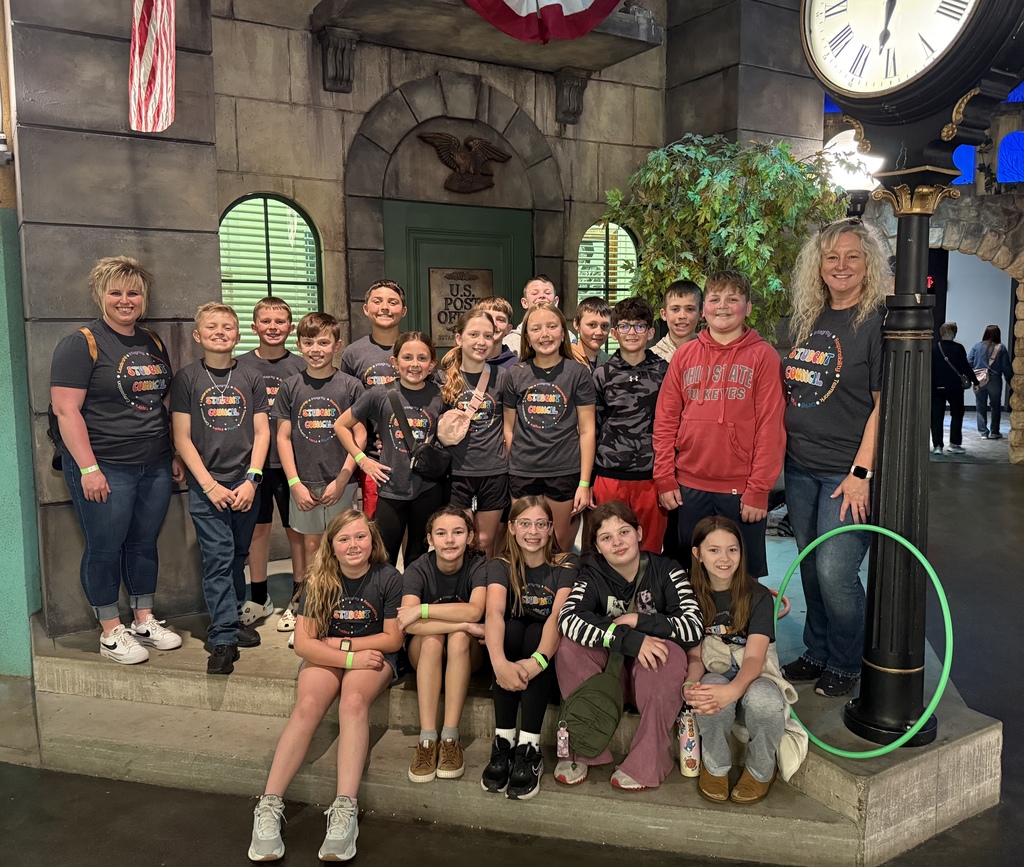 Students posing with Student Council advisors in front of a brick building with a clock tower