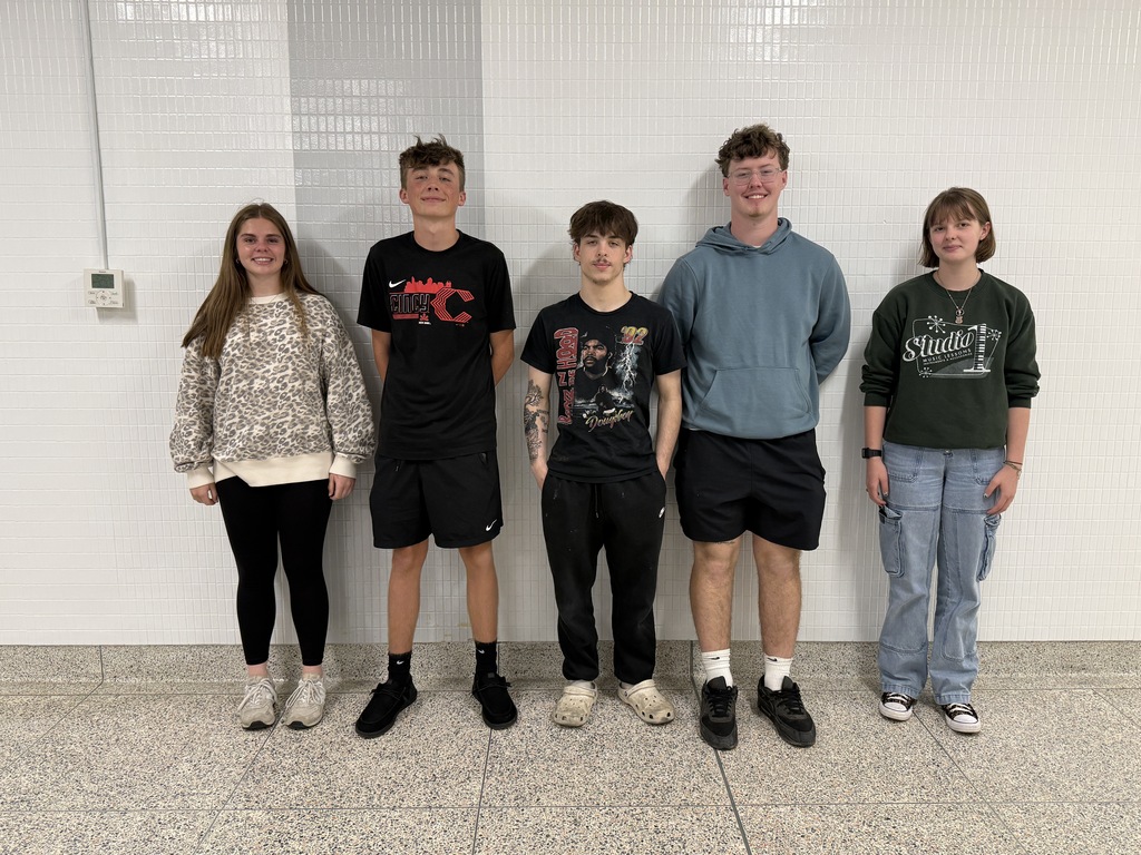 Coed students standing in front of a white and grey tiled wall