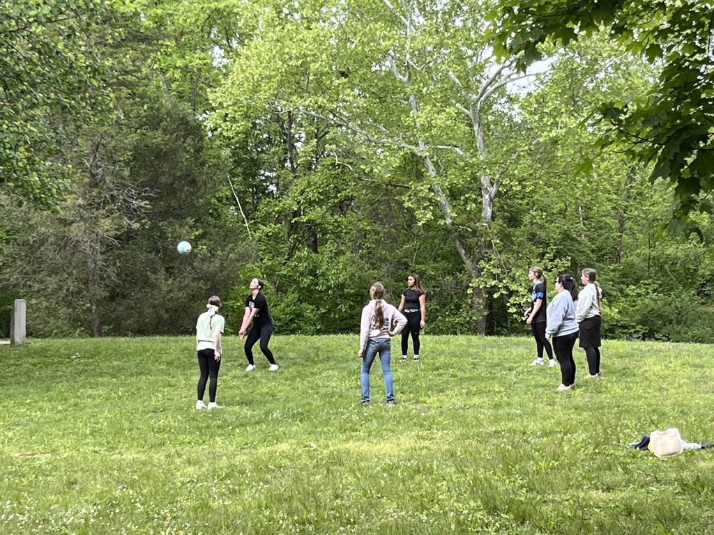 Students playing volleyball in a grassy field
