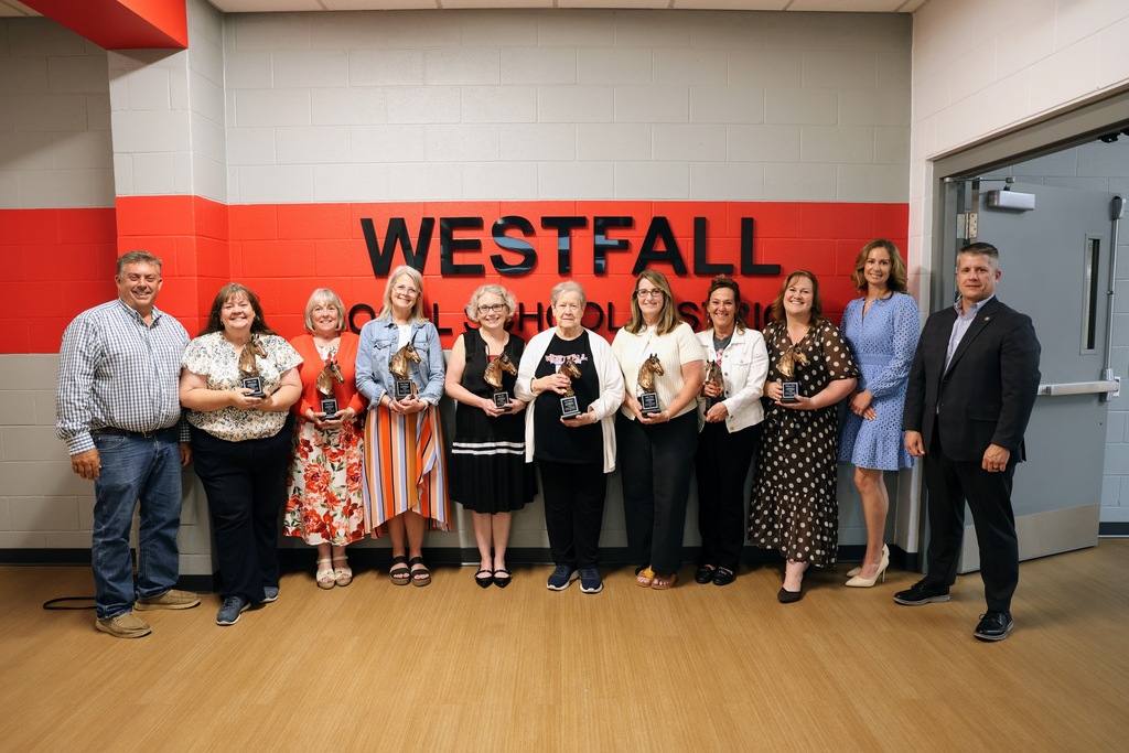 Retiring staff members posing with their horse statues alongside board of education members and superintendent
